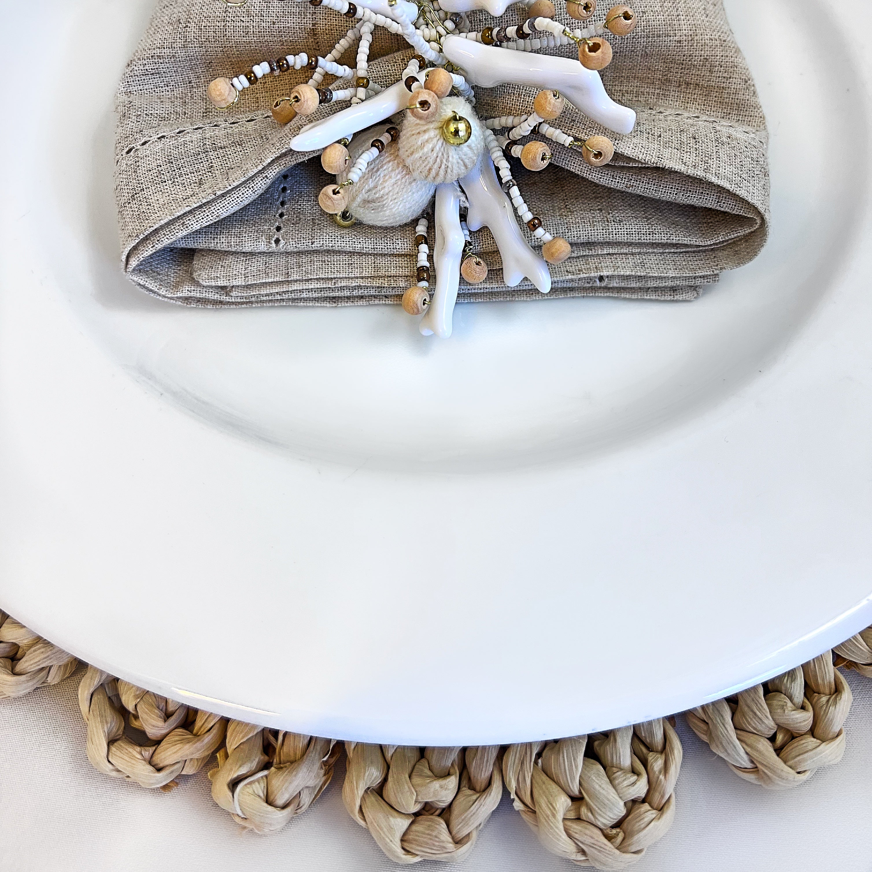 Tablescape table accessories, beaded napkin rings, linen napkins and placemats.